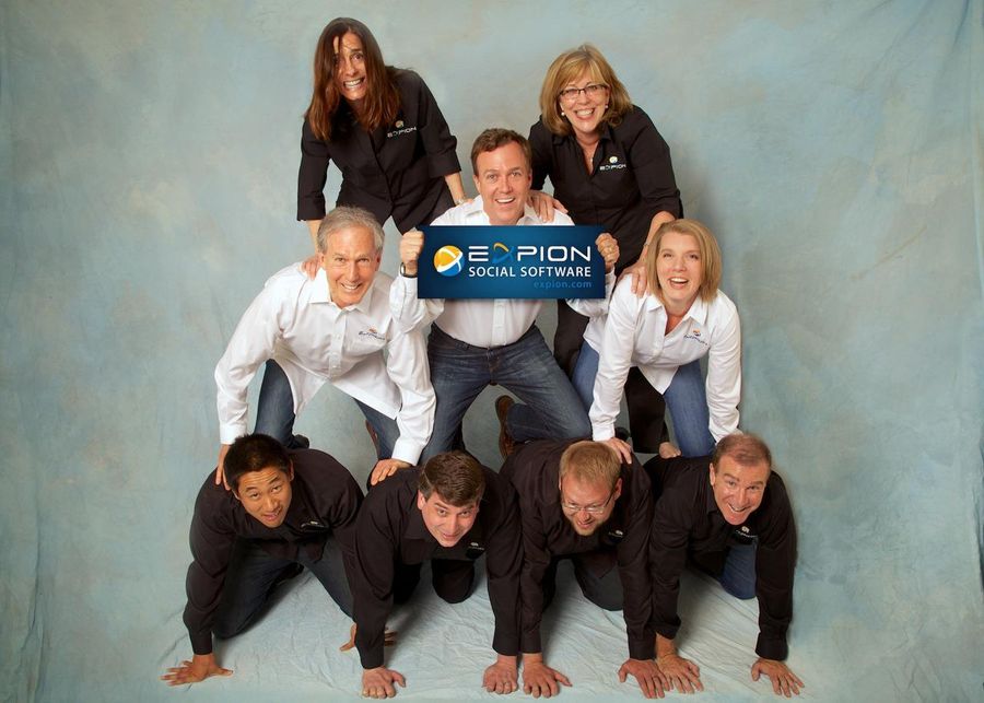 The Expion team stacked in a human pyramid, holding an Expion Social Software sign
