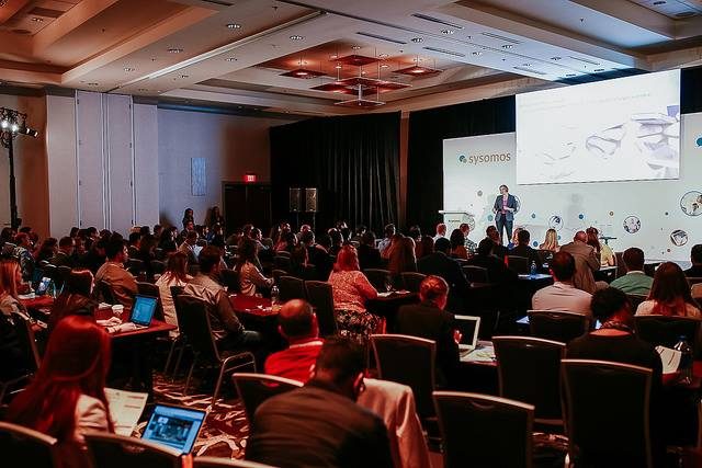 Erica Jenkins speaking on stage to a full conference room at a Sysomos event